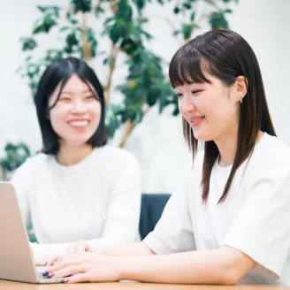 ノートPCを見ながら笑顔で話す社員